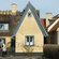 3 people standing in front of a stucco home with a thatched roof